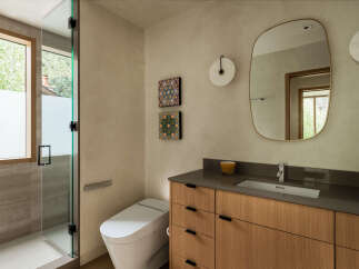 This modern bathroom features a sleek glass-enclosed shower with a large window overlooking lush greenery.