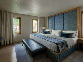 Experience luxurious comfort in this master bedroom, featuring a king-sized bed with a striking blue upholstered headboard and a decorative runner.