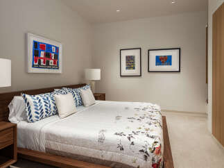 This modern bedroom features a luxurious king-size bed with a floral-patterned duvet and blue leaf-patterned throw pillows.
