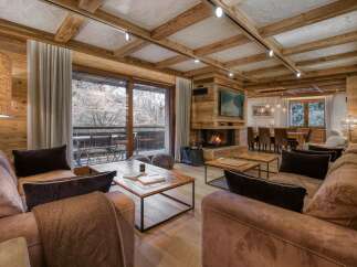 Experience luxurious mountain living in this stunning chalet-style living room, featuring a cozy fireplace and exposed wooden beams.