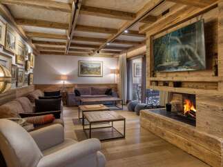 Experience rustic luxury in this stunning living room, featuring a grand fireplace with a natural wood finish and a large flat-screen TV.