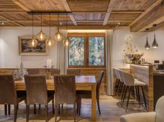 Experience rustic elegance in this dining area, featuring a warm wooden table surrounded by woven chairs, perfect for intimate gatherings.