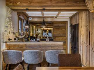 Experience rustic luxury in this charming chalet kitchen, featuring warm wooden accents and a stylish bar area perfect for entertaining.