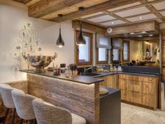 Experience rustic luxury in this stunning mountain kitchen, featuring a warm wooden bar with integrated lighting and comfortable seating.