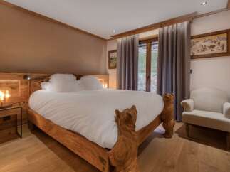 Experience rustic charm in this beautifully appointed bedroom, featuring a unique wooden bed frame with carved bear accents.