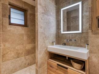 Experience rustic elegance in this bathroom, featuring warm travertine tile walls and a charming wooden vanity.