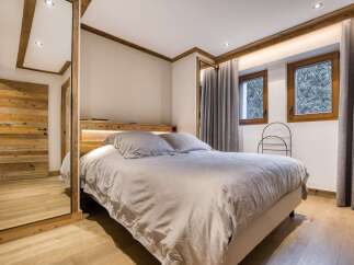 Experience rustic charm in this cozy bedroom, featuring a comfortable bed with plush linens and a wooden headboard with integrated lighting.