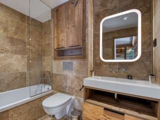 Experience luxury in this modern bathroom, featuring elegant travertine tiles and a sleek white vanity with ample wooden storage.