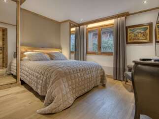 Experience cozy mountain living in this charming bedroom, featuring a plush queen-size bed with a quilted cover and ambient lighting.