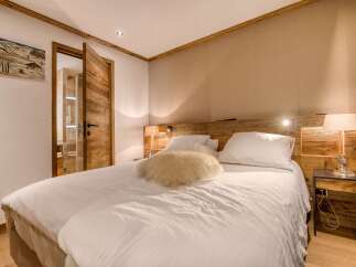 Experience cozy mountain living in this charming bedroom, featuring a plush white duvet, a unique furry accent pillow, and warm wooden accents throughout.