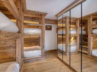 Experience cozy mountain living in this charming bedroom featuring rustic wooden bunk beds with integrated lighting.