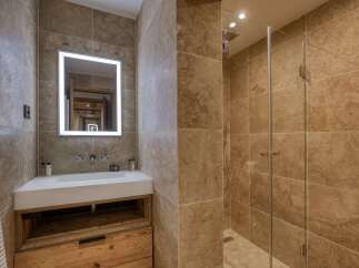 Experience luxury in this modern bathroom featuring a sleek white vanity with ample wooden storage, complemented by a large, illuminated mirror.