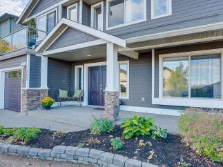 This stunning home boasts a welcoming covered porch with a charming bench and vibrant yellow flowers, leading to elegant double doors.