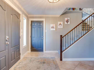 Step into a welcoming entryway featuring a stylish blue front door and a complementary gray double door.