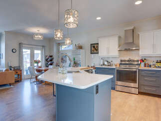 This spacious open-concept kitchen and living area features a modern island with a waterfall countertop, perfect for casual dining and entertaining.