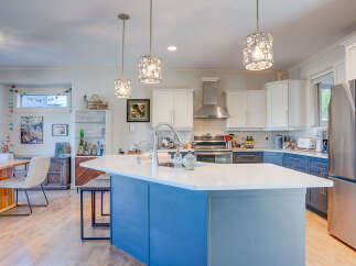 This spacious kitchen boasts a large central island with a white quartz countertop, perfect for meal prep and casual dining.