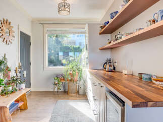 This charming kitchen boasts a warm butcher block countertop, perfect for meal preparation and casual dining.