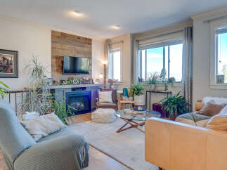 Step into this inviting living room, featuring a modern fireplace with a rustic wood-paneled accent wall and a mounted television.