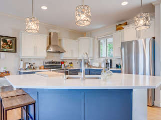 This stunning kitchen boasts a large white quartz island with a sleek faucet, perfect for meal prep and casual dining.