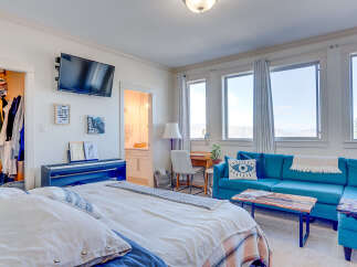 This spacious bedroom offers a comfortable and functional living space, featuring a large blue sectional sofa perfect for relaxation and entertainment.
