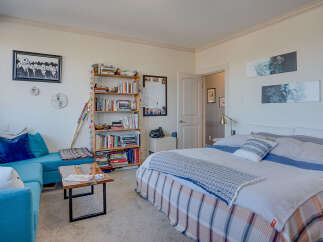 This cozy bedroom features a comfortable bed with a plaid blanket and a decorative throw, perfect for relaxation.