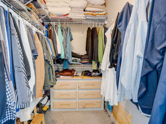 Maximize your storage with this spacious walk-in closet, featuring ample shelving and a convenient dresser with drawers.