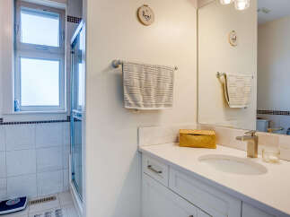 This bright and airy bathroom features a spacious vanity with a modern faucet and ample counter space.