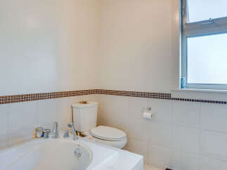 This elegant bathroom features a spacious soaking tub with chrome fixtures, perfect for unwinding after a long day.