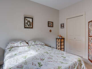 This charming bedroom features a comfortable bed adorned with a delicate floral comforter, creating a serene and inviting atmosphere.