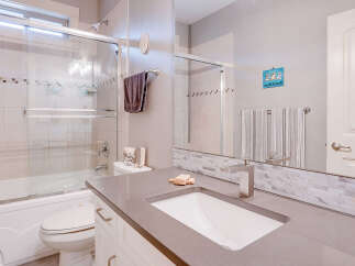 This modern bathroom features a sleek vanity with a undermount sink and a brushed nickel faucet, complemented by a marble tile backsplash.