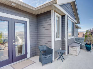 Enjoy outdoor living on this spacious balcony, featuring a comfortable wicker chair and a convenient side table.
