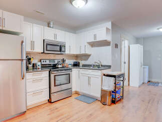 This bright and functional kitchen features sleek stainless steel appliances, including a refrigerator, microwave, and oven, complemented by clean white cabinetry and granite countertops.