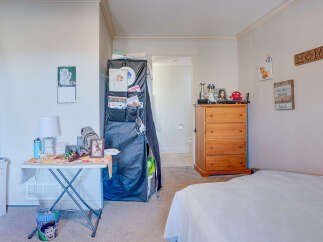 Discover this charming bedroom featuring a cozy bed and a functional wooden dresser, perfect for storage.