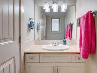 This bright and airy bathroom features a spacious vanity with a beige countertop and a white undermount sink, complemented by sleek chrome fixtures.