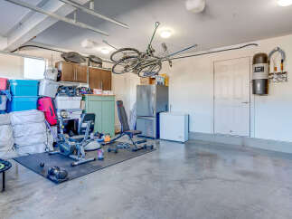 This spacious garage offers ample storage solutions with overhead shelving, cabinets, and large bins.