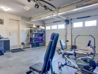 This spacious garage offers a dedicated home gym setup, complete with a Marcy exercise bike and a weight bench, perfect for your fitness routine.