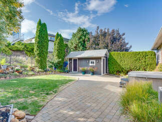 Enjoy outdoor living in this beautifully landscaped backyard featuring a charming shed, a relaxing hot tub, and a spacious patio perfect for entertaining.