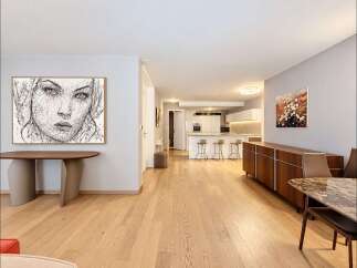 Experience modern living in this spacious open-concept apartment, featuring a sleek white kitchen with a breakfast bar and ample counter space.