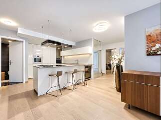 Experience modern luxury in this stunning kitchen featuring sleek white cabinetry, a spacious island with bar seating, and integrated appliances.