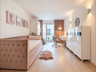 Discover this charming studio apartment featuring a plush velvet daybed, a dedicated workspace with a modern desk and chair, and ample storage solutions.