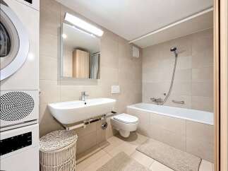 This modern bathroom features a stacked washer and dryer for ultimate convenience.