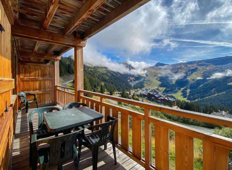 Enjoy breathtaking mountain views from this charming wooden balcony, complete with a table and chairs for al fresco dining.