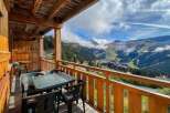 Enjoy breathtaking mountain views from this charming wooden balcony, complete with a table and chairs for al fresco dining.