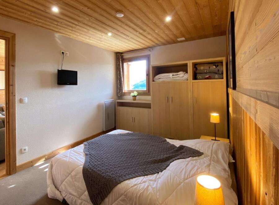 Experience cozy mountain living in this charming bedroom featuring a comfortable bed adorned with a plush grey throw.