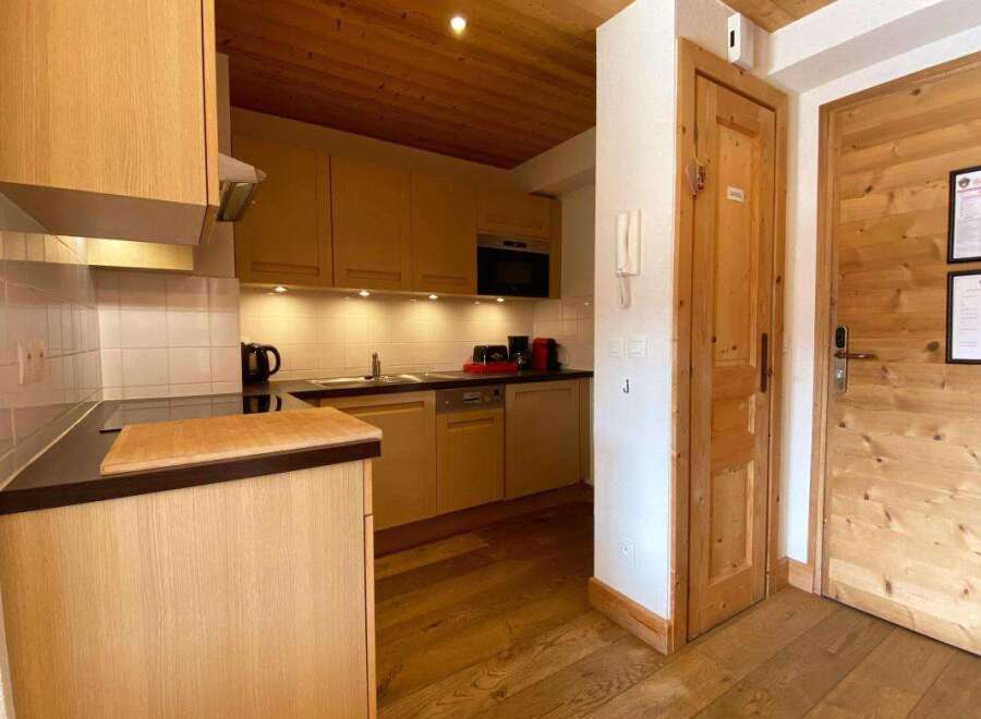 This charming kitchen features warm wooden cabinetry and a sleek countertop, perfect for meal preparation.