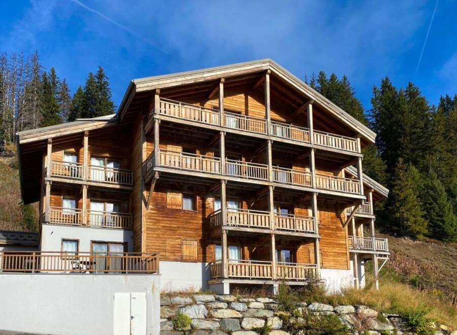 Experience alpine living in this stunning multi-story wooden chalet, nestled amidst a serene forest landscape.