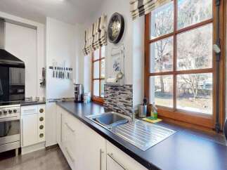 This modern kitchen boasts a sleek stainless steel range with a black glass hood, complemented by a black countertop and white cabinetry.