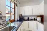 This modern kitchen features sleek white cabinetry and a dark countertop, offering ample storage and workspace.