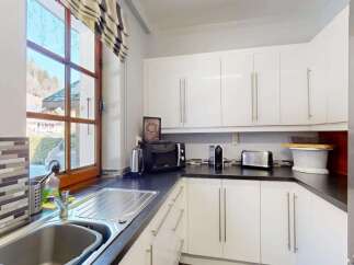 This modern kitchen features sleek white cabinetry and a dark countertop, offering ample storage and workspace.