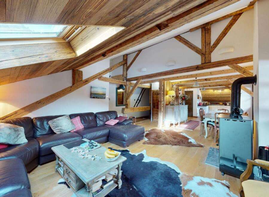 Experience rustic charm in this spacious living area, featuring exposed wooden beams and a vaulted ceiling with skylights for abundant natural light.